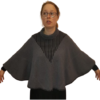 En person, der bærer briller og OPSKRIFT - MODEL HENRIETTE - PONCHO, udformet med sorte striber, står med let spredte arme. Ponchoen, med flagermus-lignende ærmer og rullekravedesign, er sat mod en hvid baggrund.