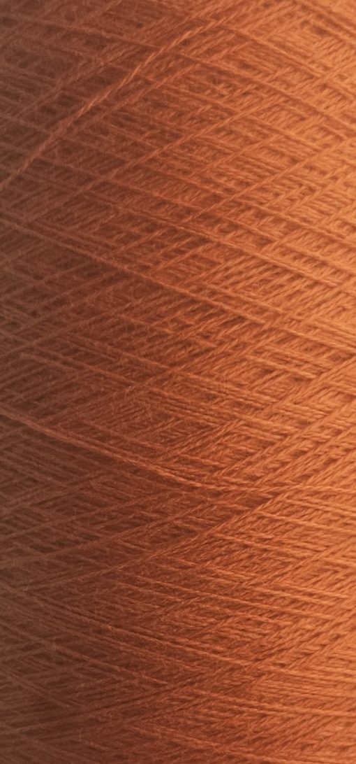 Nærbillede af Bæredygtig - økotex - bomuld nr 5714 - Orange spole med tæt viklede fibre, der skaber et tekstureret mønster. Subtil belysning fremhæver de rige farver og fine detaljer i denne miljøvenlige, økotex-certificerede bomuldsgarn.